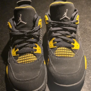 Svarta och gula Nike Air Jordans - Snygga svarta och gula Nike Air Jordans med klassisk snörning och ikonisk logga. Skorna har en sportig design med kontrasterande detaljer i gult och svart, perfekt för en stilren look.