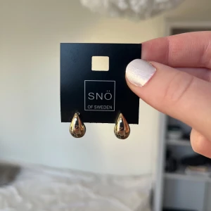 Guldpläterade örhängen från SNÖ of Sweden - Snygga guldpläterade örhängen från SNÖ of Sweden i en elegant droppform. Perfekta för att ge en stilren touch till din look. Helt oanvända och kommer på originalkortet.