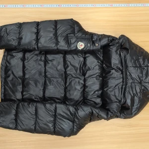 Svart dunjacka från Moncler - Säljer en snygg svart dunjacka från Moncler. Jackan har en quiltad design med dragkedja och en huva för extra värme. Perfekt för kyliga dagar. Moncler-loggan är broderad på ärmen. NFC finns med 