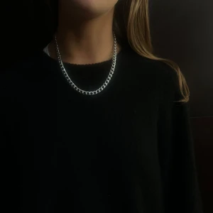 014 - Elegant silverfärgat halsband med en klassisk kedjedesign. Perfekt för att ge en stilren touch till vilken outfit som helst. Passar både till vardag och festliga tillfällen.