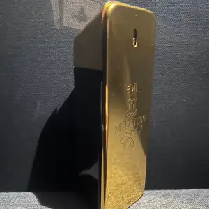 Säljer en lyxig parfym från Paco Rabanne, 1 Million, med en ikonisk guldflaska som ser ut som en guldtacka. Flaskan har en elegant och modern design med märkets logotyp ingraverad. Perfekt för den som vill ha en doft som utstrålar självsäkerhet och stil. Ca 65% av parfymen är kvar.