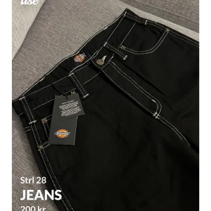 Svarta jeans från Dickies - Snygga svarta jeans från Dickies med kontrasterande vita sömmar. Klassisk design med fem fickor och en bekväm passform. Perfekta för en stilren look.