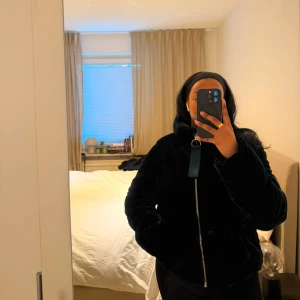 Mörkblå teddyjacka - Säljer en mysig mörkblå teddyjacka med dragkedja. Jackan har en hög krage och en cool, pösig stil. Perfekt för att hålla sig varm och stilren under kyliga dagar. Jackan är från BERSHKA