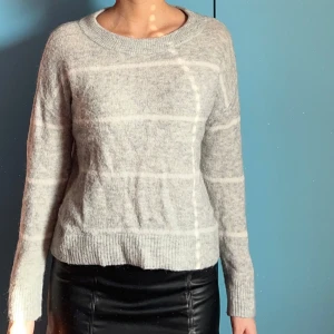 Stickad tröja från H&M - En grå/vit randig stickad tröja från H&M. Stretchig, jag är 173 cm och är lite kort på mig.