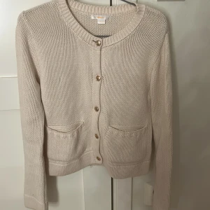 Beige stickad kofta från Gina Tricot - Säljer en super fin  beige stickad kofta från Gina Tricot med fina guldfärgade knappar. ☺️Koftan har långa ärmar och praktiska fickor framtill. Köpt för skolavslutning så använd ungefär 2 gånger. Kan diskutera pris vid snabbaffär☺️☺️