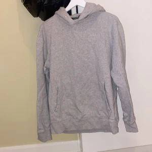 Grå hoodie från J.Lindeberg - Säljer en stilren grå hoodie från J.Lindeberg. Den har en klassisk design med en liten logotyp på bröstet och en bekväm huva. Perfekt för en avslappnad look.