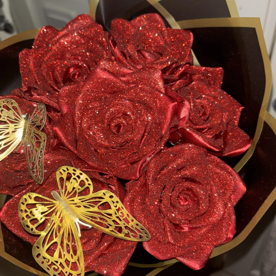 Glittrig bukett med röda rosor och fjärilar