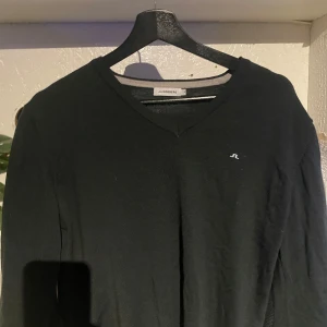 Mörkgrön tröja från J.Lindeberg - Säljer en stilren mörkgrön tröja från J.Lindeberg med v-ringning och diskret logga på bröstet. Perfekt för en klassisk look. Passar bra till både jeans och chinos.