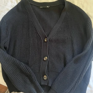 Svart stickad kofta  - Säljer en stilren svart stickad kofta. Koftan har en v-ringad design med tre knappar framtill och långa ärmar. Perfekt för kyligare dagar och enkel att matcha med olika outfits. Köpt second hand så lite sliten men har fortfarande mycket att ge☺️