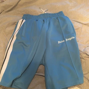 Blå shorts från Palm Angels - Snygga blå shorts från Palm Angels med vita sidoremsor och elastisk midja med snörning. Perfekta för en avslappnad stil. Oversized i storleken