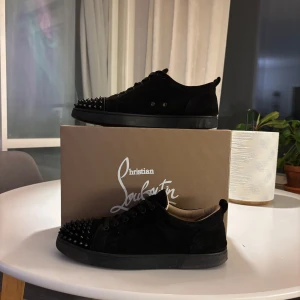 Svarta sneakers från Christian Louboutin - Snygga svarta sneakers i mocka från Christian Louboutin med ikoniska röda sulor. Skorna har snörning och är dekorerade med svarta nitar på tån för en edgy look. Pristet är inte hugget i sten! Va inte rädd för att ställa frågor. Skick 5/10