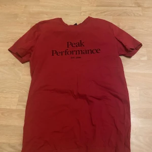 Röd t-shirt från Peak Performance - Säljer en röd t-shirt från Peak Performance med tryck på framsidan. T-shirten är kortärmad och har en klassisk passform. Sparsamt använd! Riktigt fräsig 🔥 pris går att diskutera vid snabb affär 