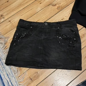 Svart minikjol med paljetter - Snygg svart minikjol med glittrande paljettdetaljer på fram- och baksidan. Lågmidjade och sjuuukktt snygg. 