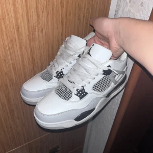 Vita och svarta sneakers - Snygga vita och svarta sneakers med snörning och ikonisk logga på hälen. Perfekta för en stilren look med en sportig touch.