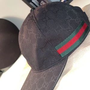 Svart keps med mönster och randig detalj - Säljer nu en perfekt Gucci keps inför sommarn, sitter sänkt och går att rocka till allt, dush bag medföljer såklart, kepsen är i str S och har en skick på 10/10 tveka inte för höra av för flera bilder eller frågor 