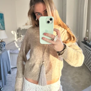 Beige stickad tröja - Säljer en mysig beige stickad tröja med långa ärmar. Perfekt för kyligare dagar och enkel att matcha med olika outfits. Tröjan har en klassisk design och är ett måste i garderoben.