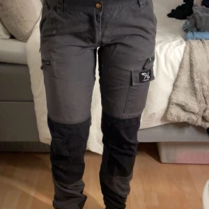 Grå Nordwand Pants från RVRC - Säljer ett par grå Nordwand Pants från RVRC. Byxorna har flera praktiska fickor med dragkedjor och en justerbar midja. Slitstarkt material och perfekt för utomhusaktiviteter.
