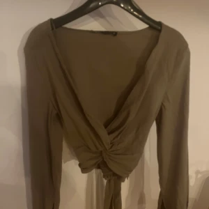 Khaki grön omlottopp från Zara - Säljer en stilren khaki grön omlottopp från Zara med långa ärmar och knytning baktill. 