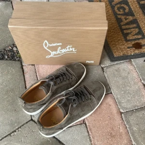 Christian loubitin - Snygga gråa sneakers i mocka från Christian Louboutin med den ikoniska röda sulan. Skorna har snörning och en stilren design som passar perfekt för en trendig look. Har kvitto och allt og följer med även med ett par extra snören vid köp. Hör av dig vid minsta lilla fundering.