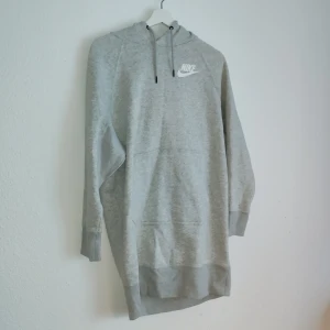Grå hoodie från Nike - Säljer en stilren grå hoodie från Nike med klassisk logga på bröstet. Hoodien har långa ärmar och en praktisk huva med dragsko. Perfekt för en avslappnad look.