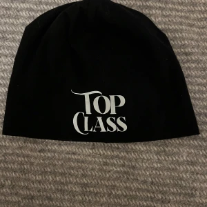 Top class music  - Snygg svart mössa med texten 'Top Class' i vitt framtill. Perfekt för att hålla värmen med stil. Enkel design som passar till det mesta.