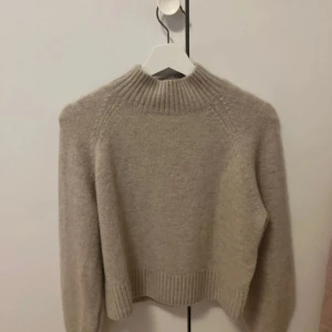 Beige stickad tröja från & Other Stories - Säljer en mysig beige stickad tröja från & Other Stories. Tröjan har en hög ribbad krage och långa ärmar. Säljer då den inte kommer till användning! Storlek: Xs