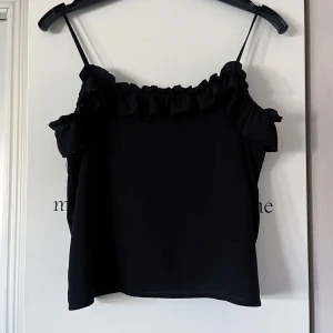 Svart linnetopp från Mango -  Svart linnetopp från Mango med smala axelband och volangdetaljer längs halsringningen. 🖤