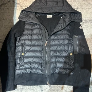 Svart jacka från Moncler - Säljer en snygg svart jacka från Moncler med quiltad design och huva. Jackan har dragkedja och ribbade detaljer. Perfekt för kyligare dagar. 🖤