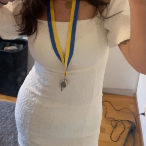 Vit klänning/student - Säljer en stilren student klänning med puffiga kortärmar och en figurnära passform. Klänningen har en fyrkantig urringning och är tillverkad i ett texturerat material som ger en elegant look. Perfekt för sommarens alla tillfällen! Köpt för 879 på zalando