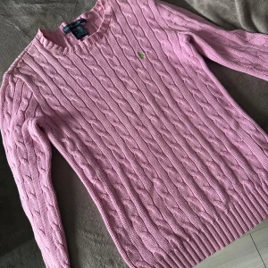 Rosa stickad tröja Ralph Lauren - Säljer en snygg rosa stickad tröja, Ralph Lauren med kabelstickat mönster. Tröjan har långa ärmar och en liten grön logga på bröstet. Perfekt för kyligare dagar! Pris går att diskuteras vid snabb affär