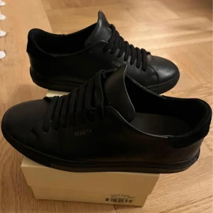 Svarta sneakers från Axel Arigato - Snygga svarta sneakers från Axel Arigato i skinn. De har en stilren design med snörning och en diskret logga på sidan. Perfekta för en minimalistisk look.