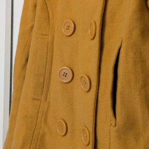 Brun kappa med knappar - Snygg brun kappa med dubbelknäppning och stora knappar. Jackan har en klassisk krage och långa ärmar. Perfekt för höst och vår med sin stilrena design. Trendig som Stockholmsstil 