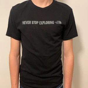 Svart t-shirt från The North Face - Säljer en svart t-shirt från The North Face med texten 'Never Stop Exploring' tryckt på framsidan. T-shirten har en klassisk passform och är kortärmad, perfekt för vardagsäventyr.