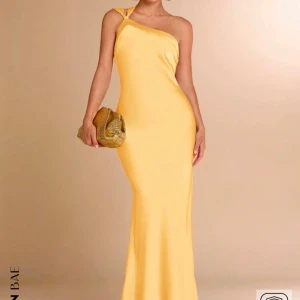 Gul one-shoulder klänning - Gul långklänning med one-shoulder design och öppen rygg. Klänningen har en knytning i ryggen som ger en snygg detalj. Köpt från SHEIN och tyvärr lite  genomskinlig❤️ passar perfekt om man vill ha en billig balklänning!! (Endast testat)