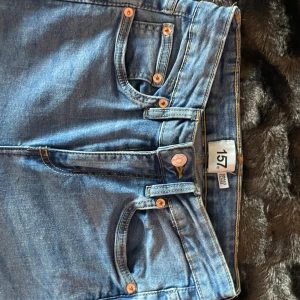 Blå jeans 'Snake Flare' - Snygga blå jeans med flare-stil från märket 157. De har en klassisk femficksdesign och knappar i kopparfärg. Perfekta för en trendig look.