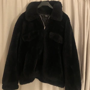Svart pälsjacka med dragkedja - Snygg och fluffig svart pälsjacka med dragkedja framtill. Jackan har en klassisk krage och långa ärmar, perfekt för kyligare dagar. Den ger en lyxig känsla och är lätt att matcha med olika outfits.🥰Pris kan diskuteras!