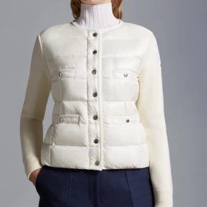 Vit dunjacka från Moncler - Säljer en stilren vit dunjacka från Moncler med knappar framtill. Jackan har långa ärmar och en quiltad design som ger en snygg look. Perfekt för kyligare dagar.            Nypris: ca-8000kr, sparsamt använd, passar personer med M och L