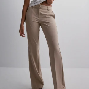 Beige kostymbyxor - Snygga beige kostymbyxor med medelhög/ låg midja och rak passform. Perfekta för en stilren look. Byxorna har en klassisk design med dragkedja och knappar framtill. Skriv på DM för fler bilder❤️