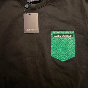 Svart tröja med grön ficka från Louis Vuitton - Snygg svart tröja från LV med grön logga på bröstet