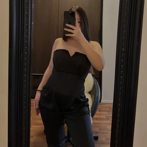 Jumpsuit - Elegant svart byxdress med tubtopp-design. Perfekt för en stilren look med en figurnära passform. Byxdressen har en enkel och chic stil som passar till många tillfällen.🥰🥰🥰
