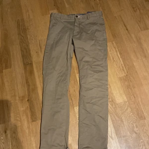 Beige chinos från GANT - Snygga beige chinos från GANT med en klassisk design. Byxorna har en rak passform och är tillverkade i ett bekvämt bomullsmaterial. Perfekta för en stilren look.