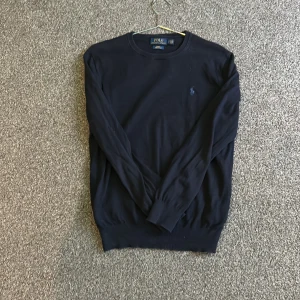 Marinblå tröja från Polo Ralph Lauren - Säljer en stilren svart tröja från Polo Ralph Lauren i Pima bomull. Tröjan har en slim fit passform och långa ärmar. Perfekt för en elegant och avslappnad look.