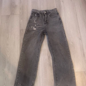 Grå jeansbyxor från Shein - Snygga grå jeansbyxor från Shein i en avslappnad stil. Byxorna har slitna detaljer på framsidan och en klassisk femficksdesign. Perfekta för en trendig och casual look.