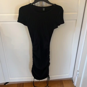 Svart ribbad klänning från SHEIN - Snygg svart ribbad klänning från SHEIN med korta ärmar och snörning i sidan för en justerbar passform. Perfekt för en stilren look. 🖤