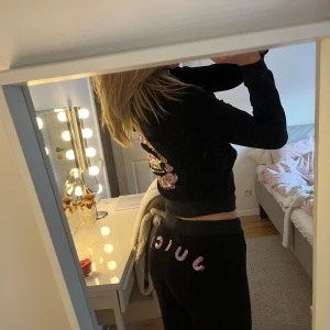 Juicy Couture dress - Säljer en svart hoodie från Juicy Couture med glittrig logga på ryggen. Tröjan har dragkedja framtill och en mysig huva. Perfekt för en avslappnad stil. Passar bra ihop med matchande byxor för en komplett look.