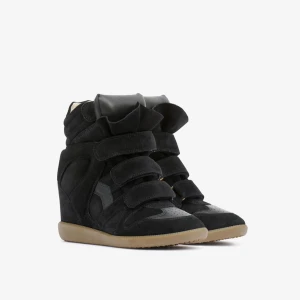 Isabel Marant skor  - Snygga svarta sneakers med kilklack och kardborreband. Skorna har en modern design med en högre ankel och en bekväm gummisula. Perfekta för att ge lite extra höjd och stil till din outfit. Väl använda skriv för fler bilder. 