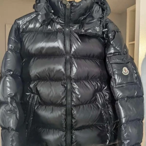 Moncler Maya - Säljer en snygg svart pufferjacka från Moncler med glansig yta och dragkedja. Kvitto finns. Kan gå ner i pris vid snabb affär!