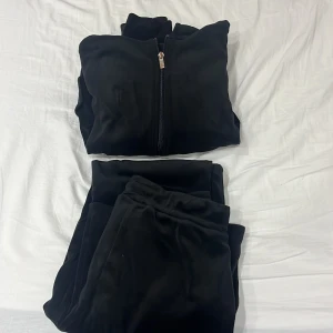 Svart mjukisbyxa med dragkedja - Säljer ett par svarta mjukisbyxor med matchande tröja. Byxorna har en bekväm passform och tröjan har en dragkedja framtill. Perfekt för en avslappnad dag hemma eller på språng.