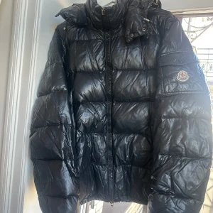 Moncler Maya (5)  - Säljer en äldre Moncler Maya vinterjacka i storlek (5). Moncler loggan som sitter på dragkedjan har tyvärr lossnat men går givetvis att köpa till den detaljen. Inget fel på själva dragkedjan i sig. 