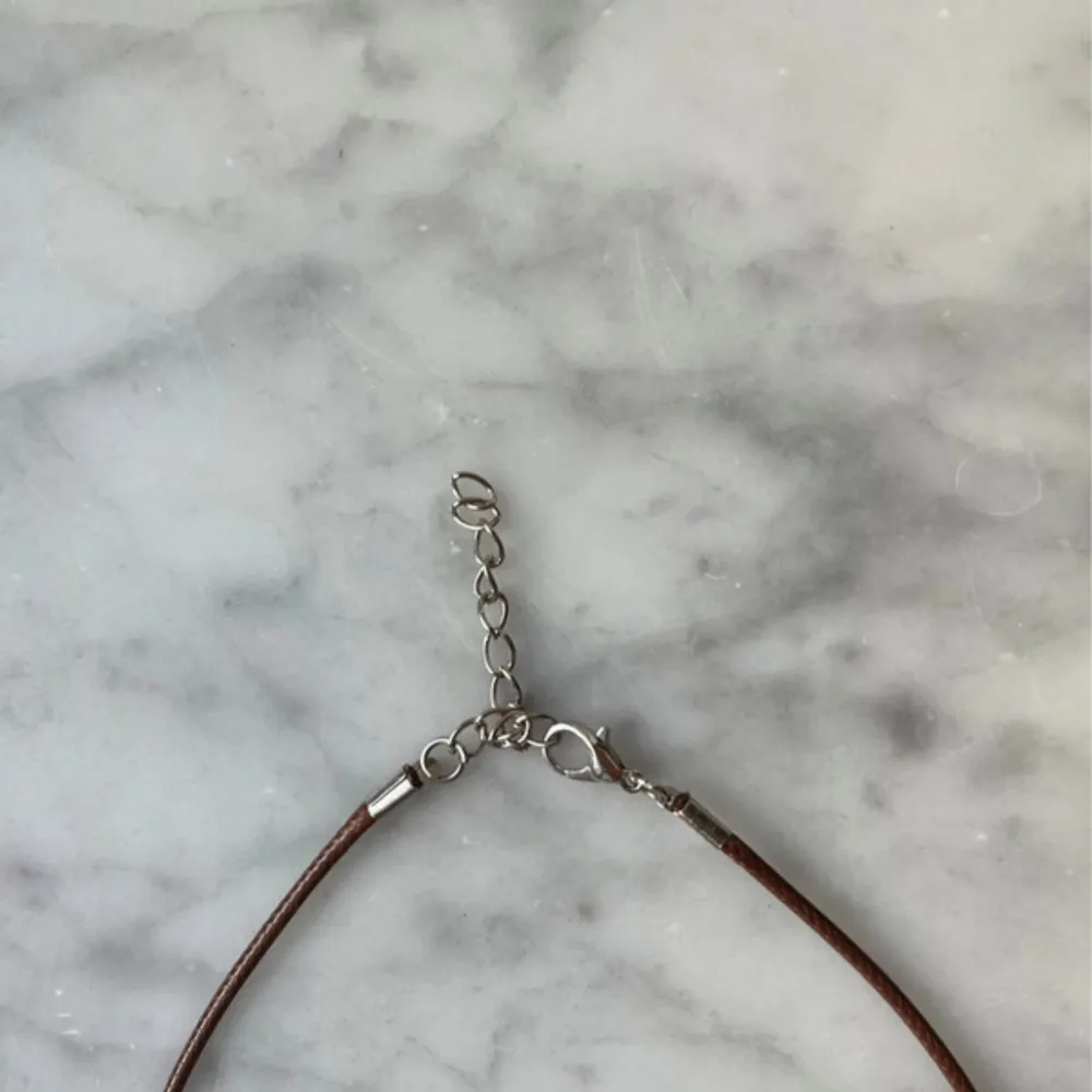 Egengjort halsband med berlock silvrig blomma gjort i aluminiumtråd, med brunt läderband/snöre, justerbart! . Accessoarer.